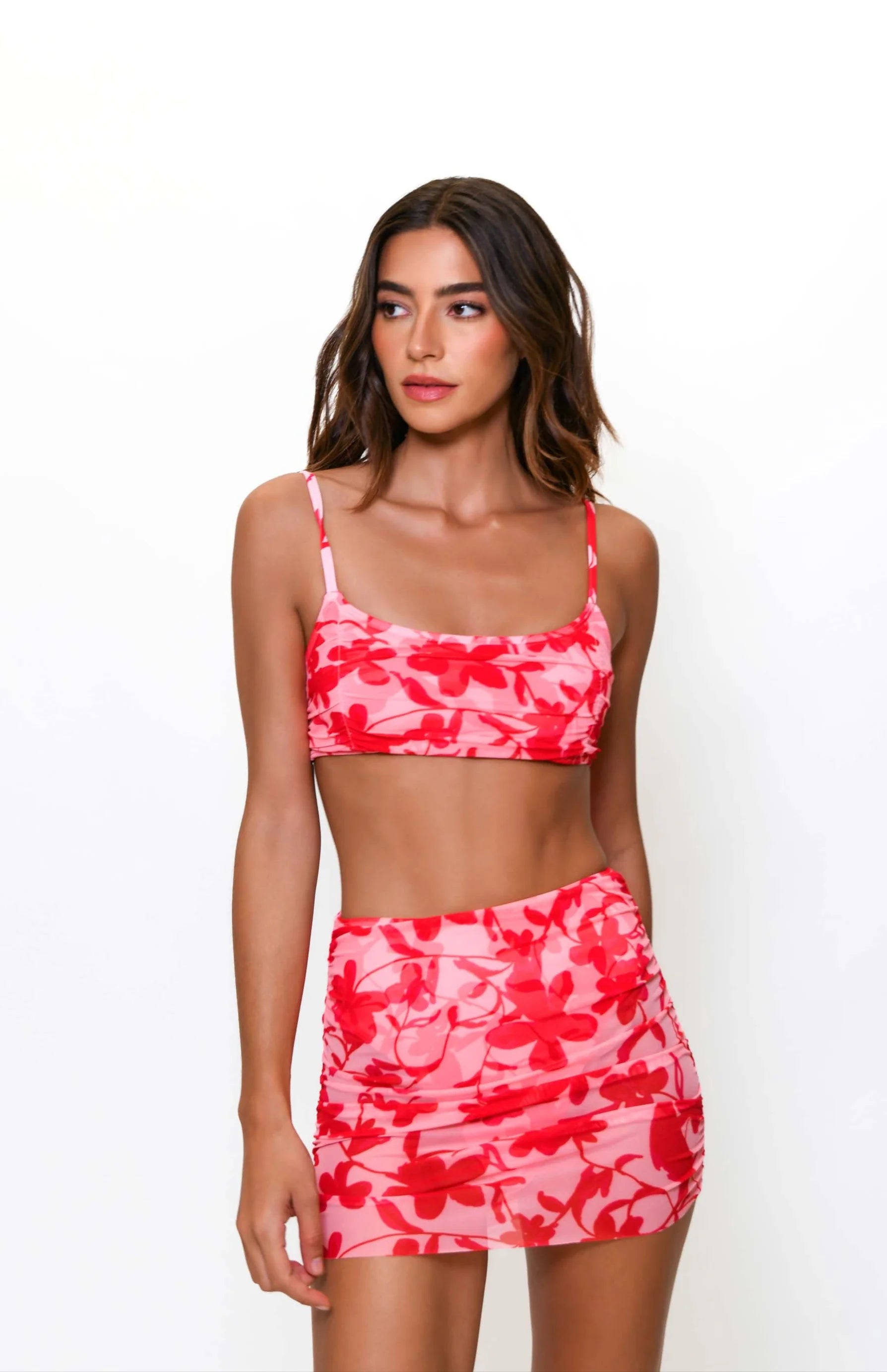 Woman wearing a red and pink camouflage two-piece swimsuit on a white background