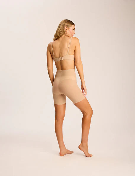 Woman wearing beige shapewear on a plain background