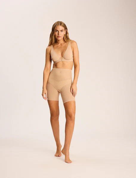 Woman wearing beige shapewear on a plain background
