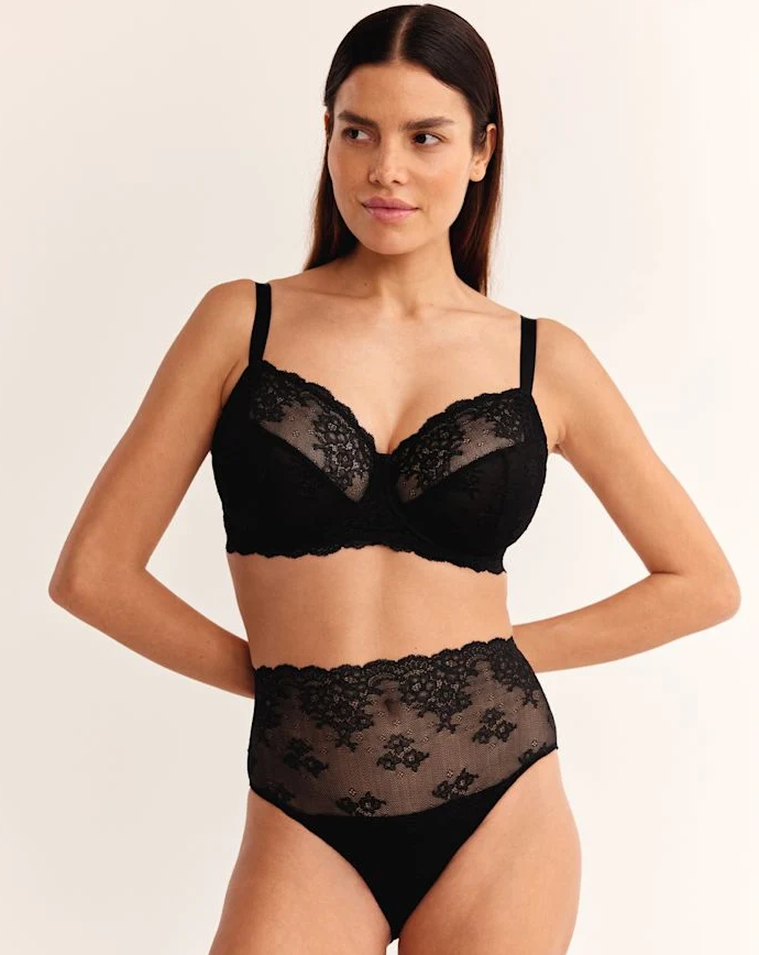 woman wearing black lace bra and underwear on a beige background 