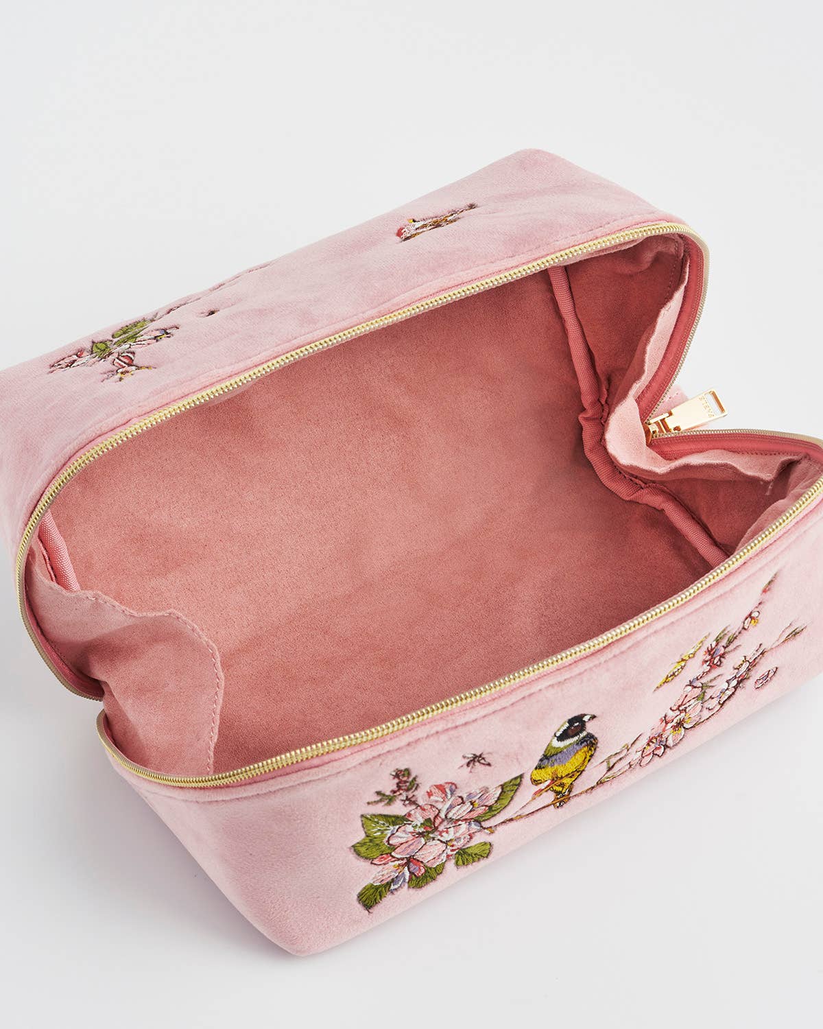 Pink velvet pouch with floral and bird embroidery on a white background