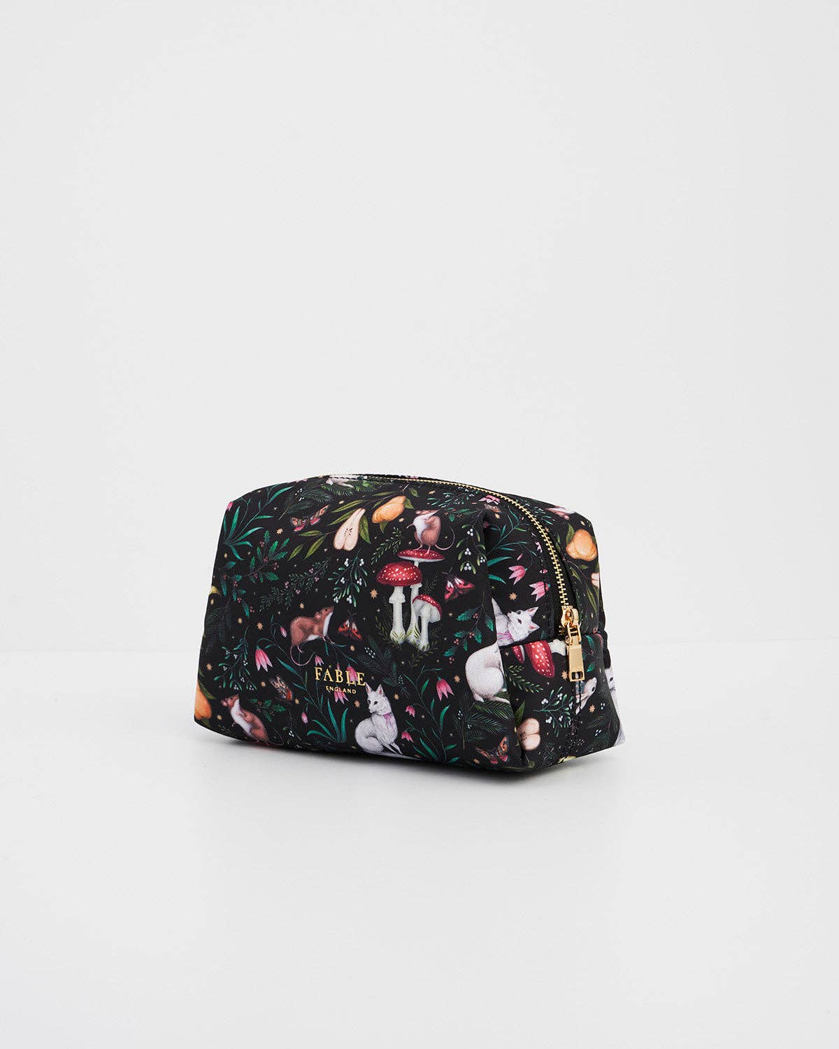 A small zippered cosmetic pouch with a black background and a colorful woodland print featuring rabbits, mushrooms, and leaves, with a gold zipper.