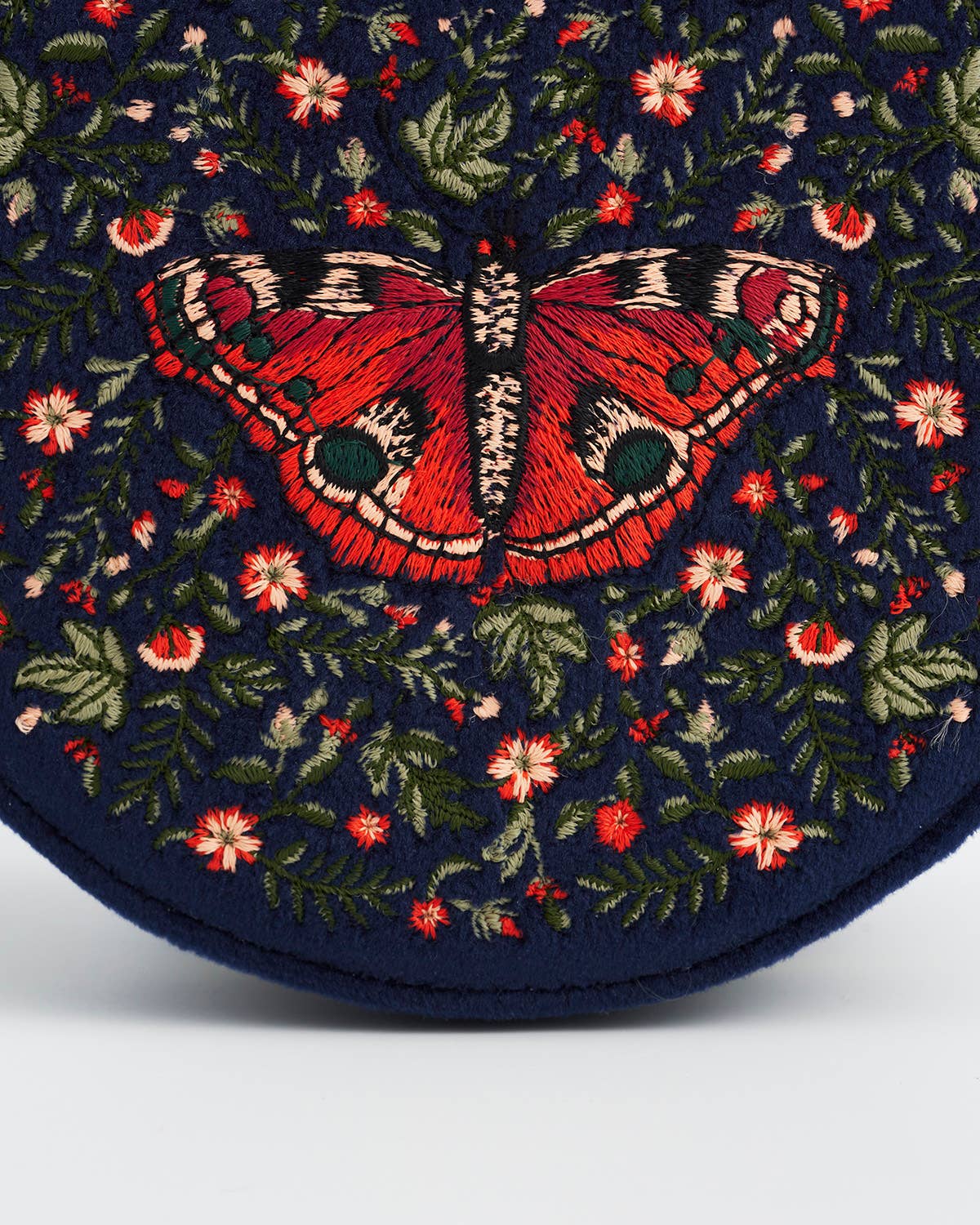 Embroidered butterfly design on a dark blue fabric with flowers