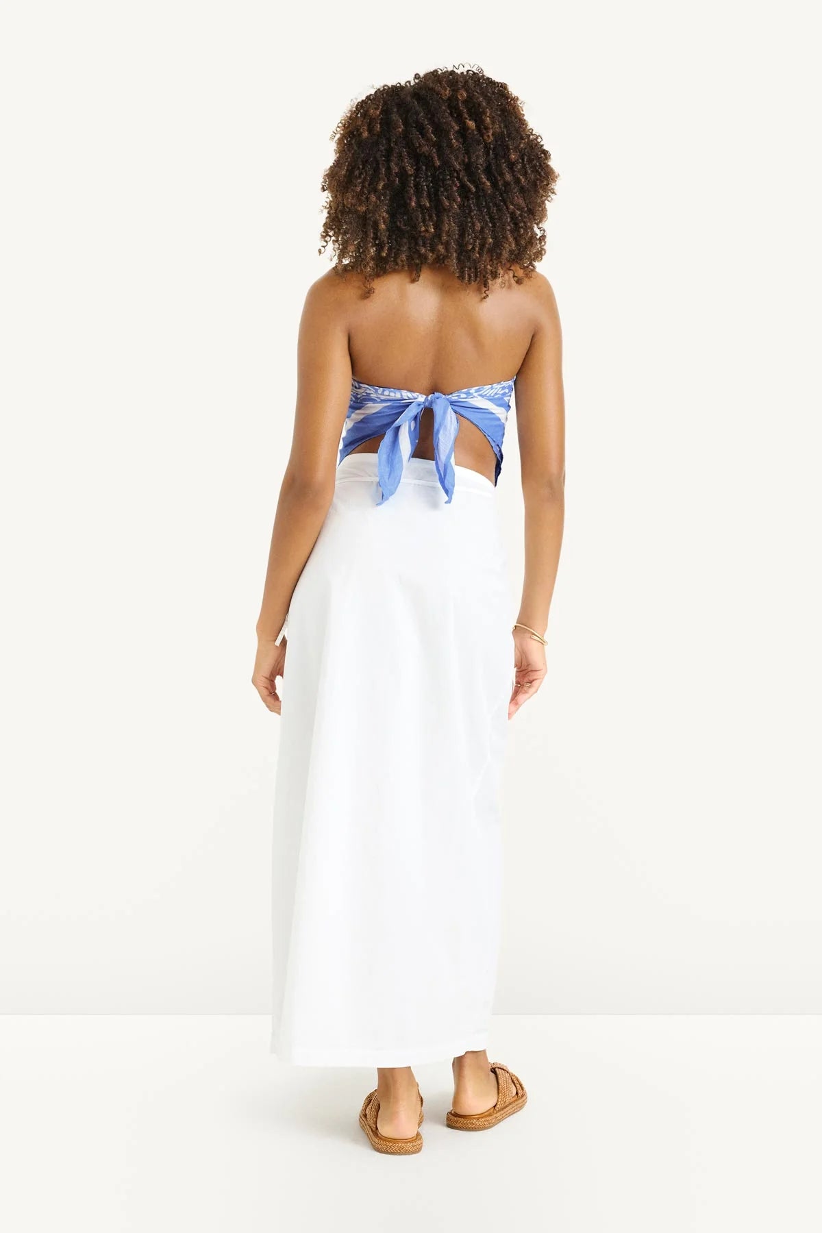 Woman wearing a white dress with a blue ribbon at the back on a white background