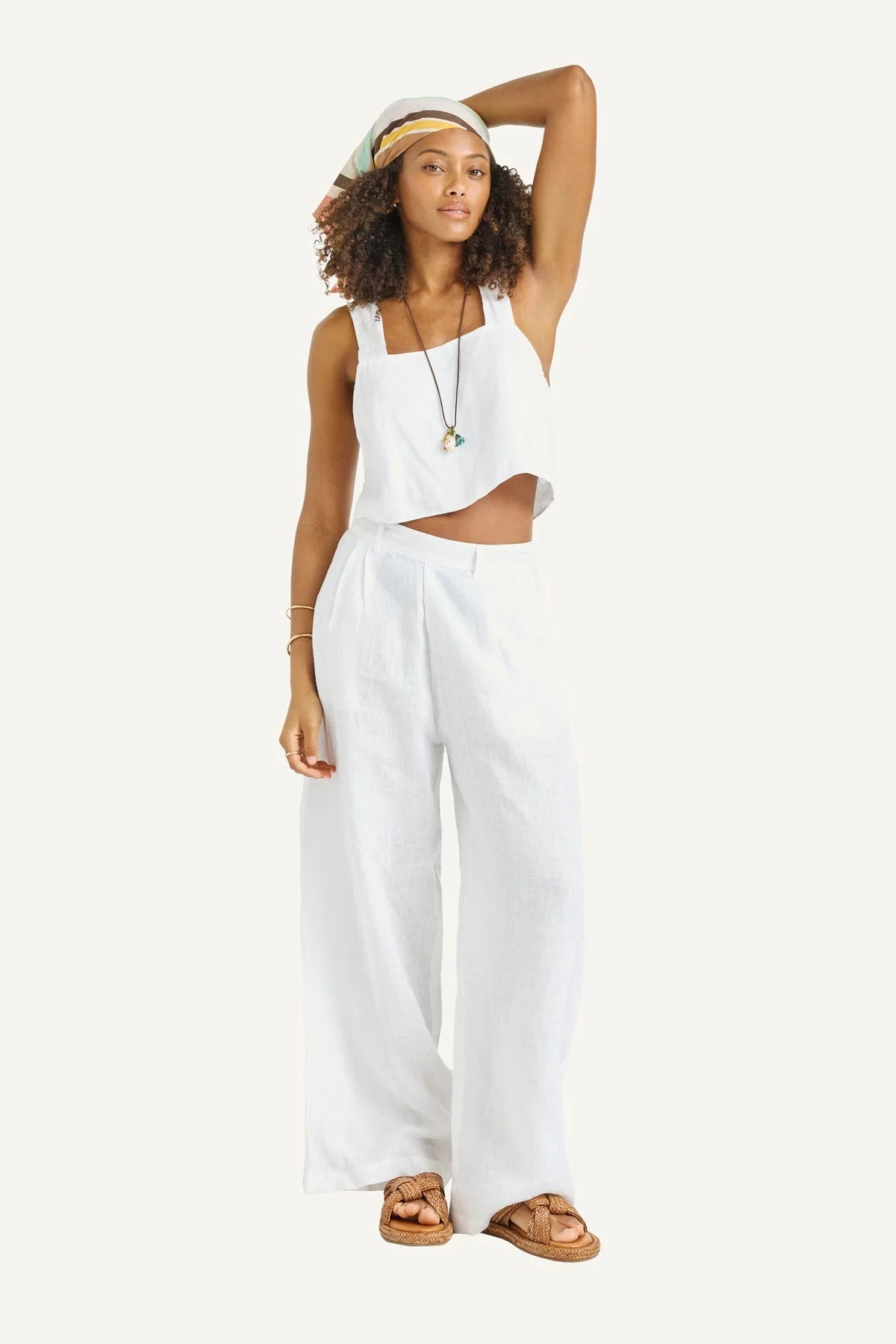 Woman wearing a white sleeveless top and wide-leg pants on a white background