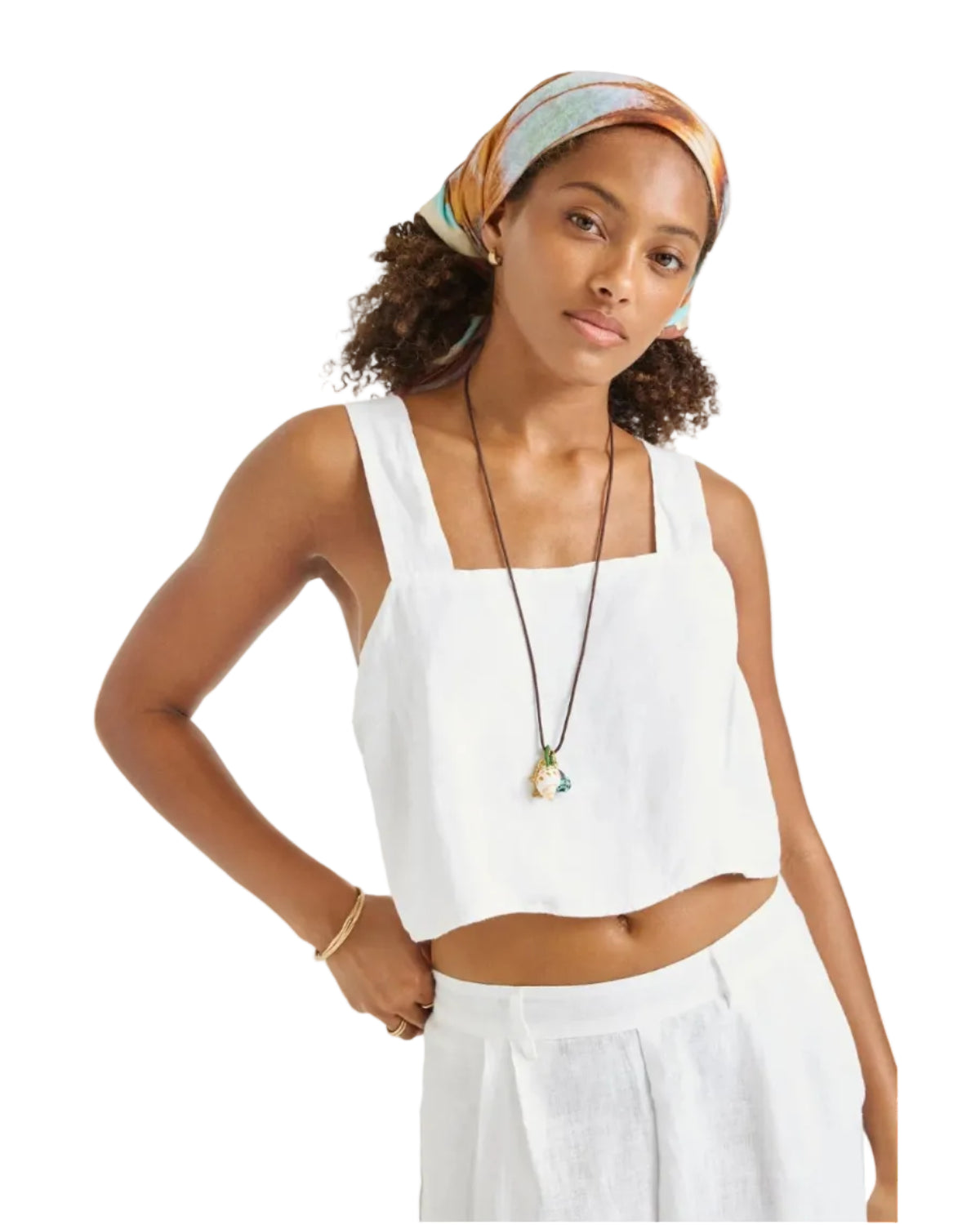 Woman wearing a white sleeveless top and white pants with a headscarf on a white background