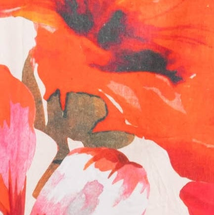 Abstract floral print close-up with large orange and red flower shapes, pink areas, and dark charcoal accents on a white background.