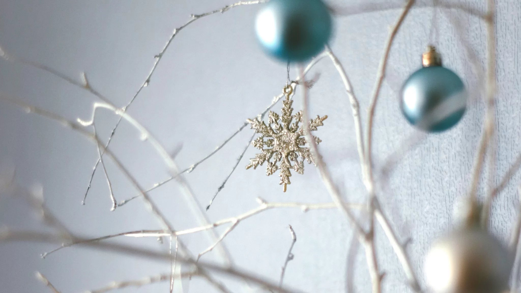 Decorative arrangement with snowflake ornament and teal ornaments on a light background