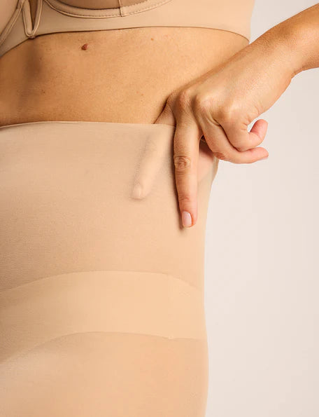 Beige shapewear being worn on a person's torso with a neutral background