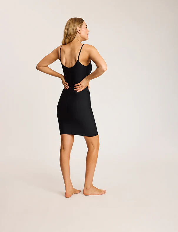 Woman wearing a black slip dress against a plain background