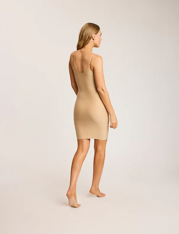 Woman wearing a beige slip dress on a plain background