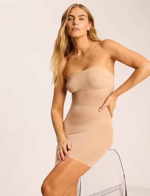 Woman wearing a beige strapless dress against a plain background