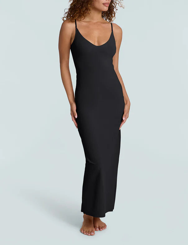 Woman wearing a black slip dress on a light gray background