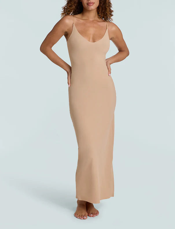 Woman wearing a beige slip dress against a light gray background