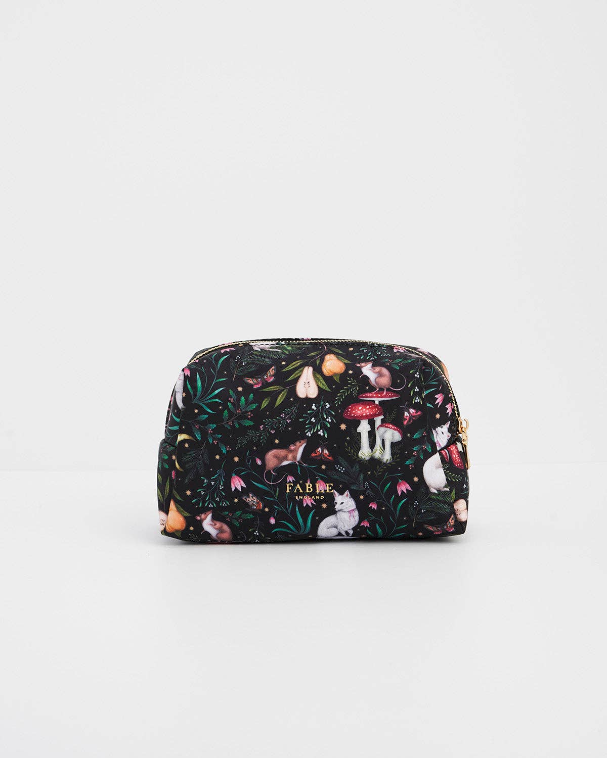 A small zippered cosmetic pouch by Farkle, featuring a whimsical woodland print with mushrooms, foxes, rabbits, and foliage on a black background, set against a plain white studio backdrop.