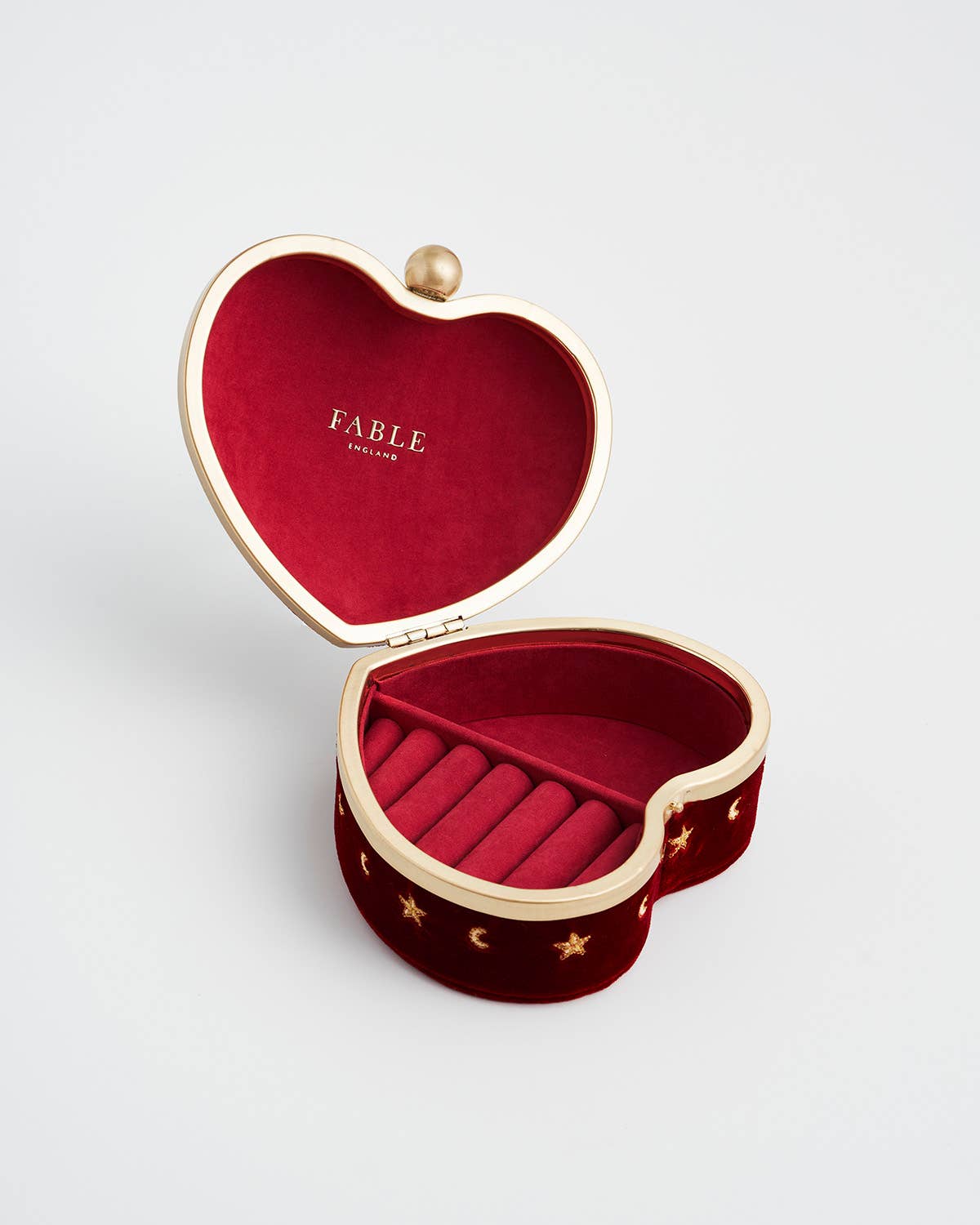 Heart-shaped jewelry box with red interior and gold accents on a light gray background