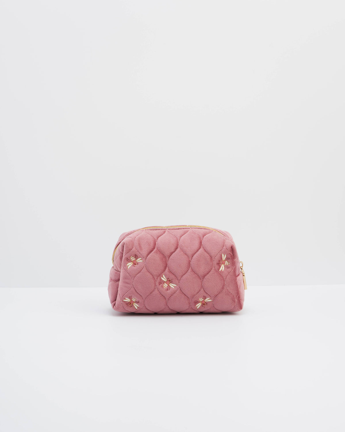 A pink quilted cosmetic pouch with embroidered floral details and a gold zipper, centered on a clean white background.