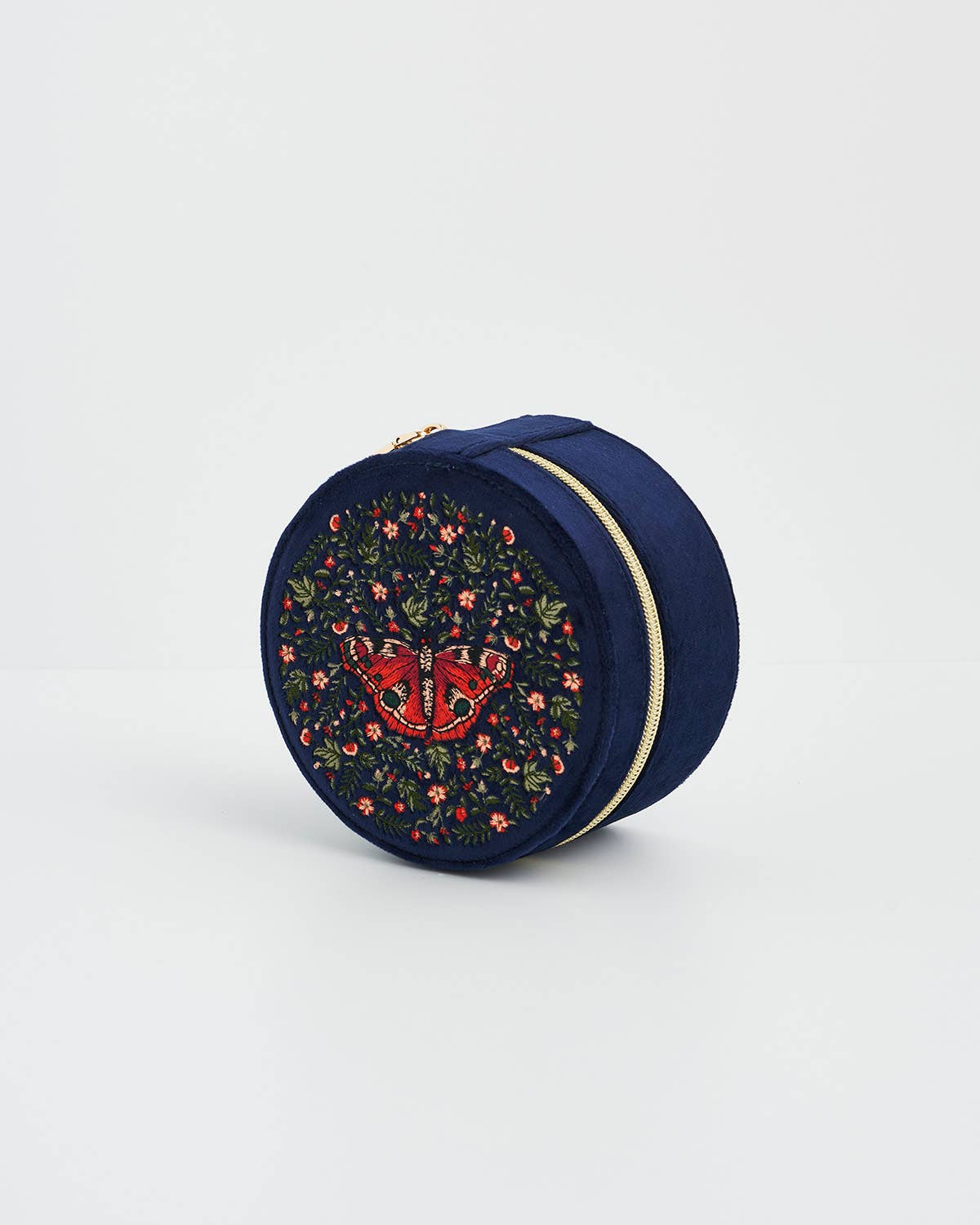 Round navy blue pouch with floral embroidery and a red heart design on a light gray background
